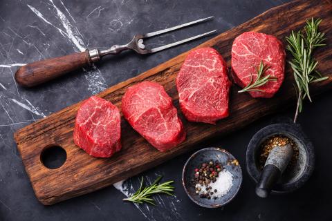 multiple tenderloin steaks on a wooden cutting board